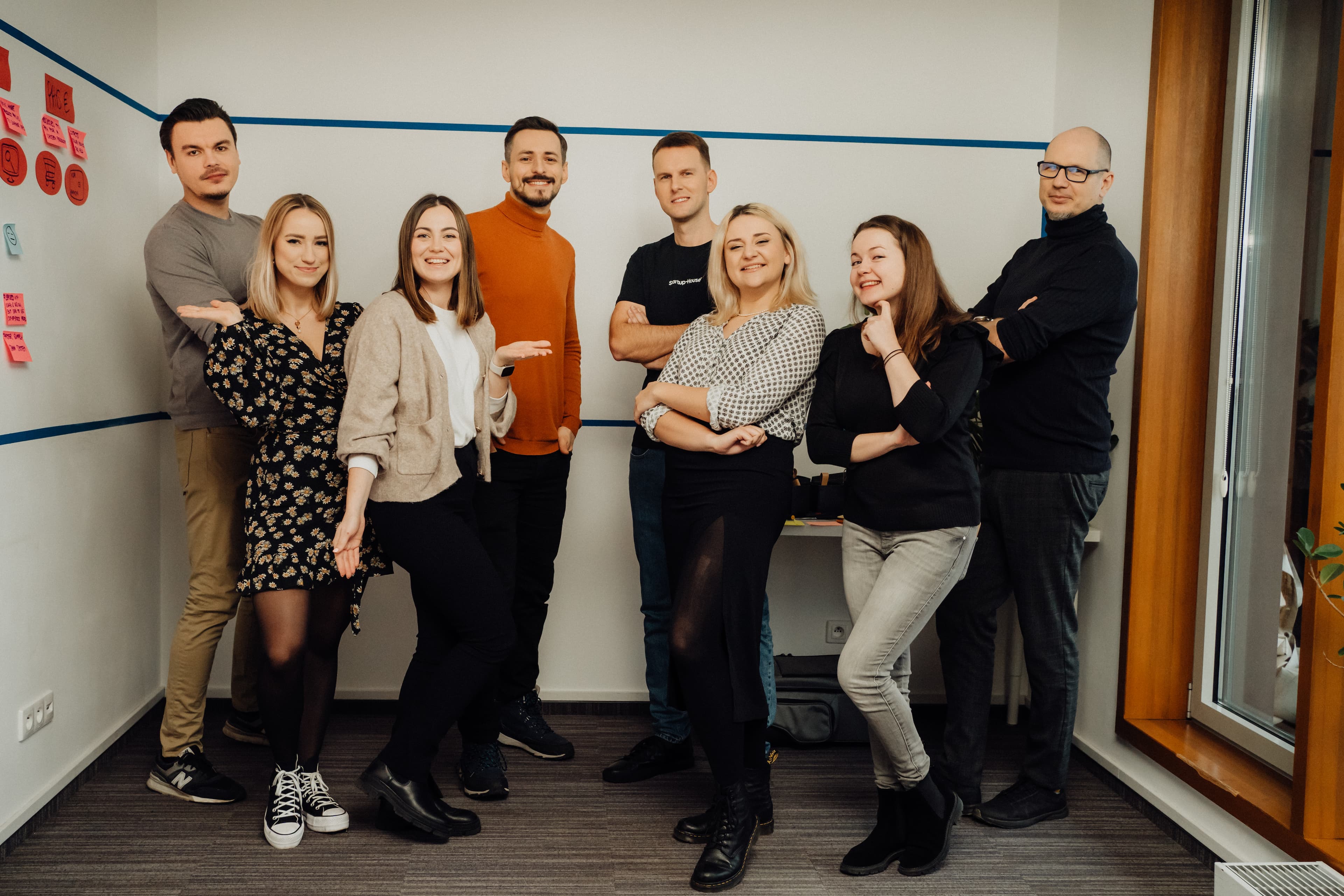 Enthusiastic team at Startup House celebrating success with thumbs up and a backdrop of office culture elements